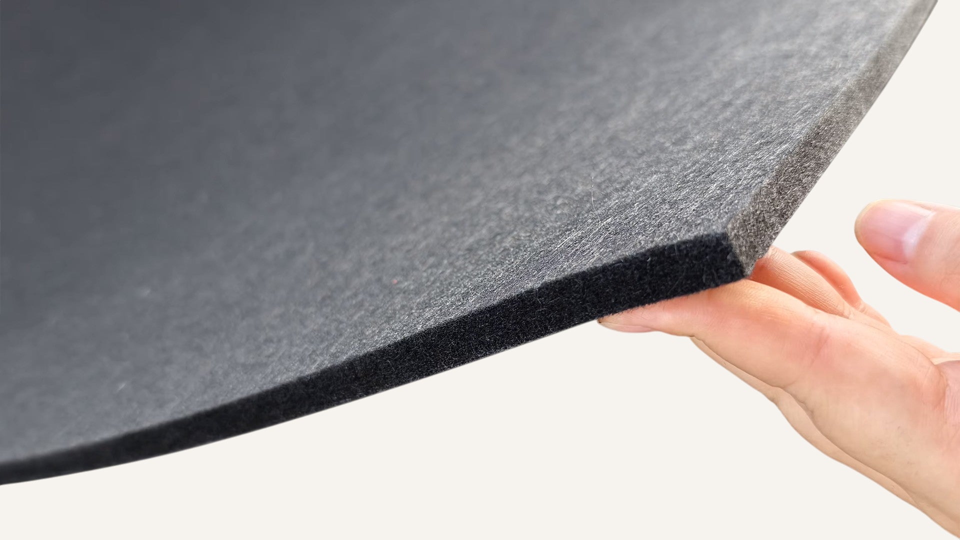 Hand holding high-density black acoustic felt backing.